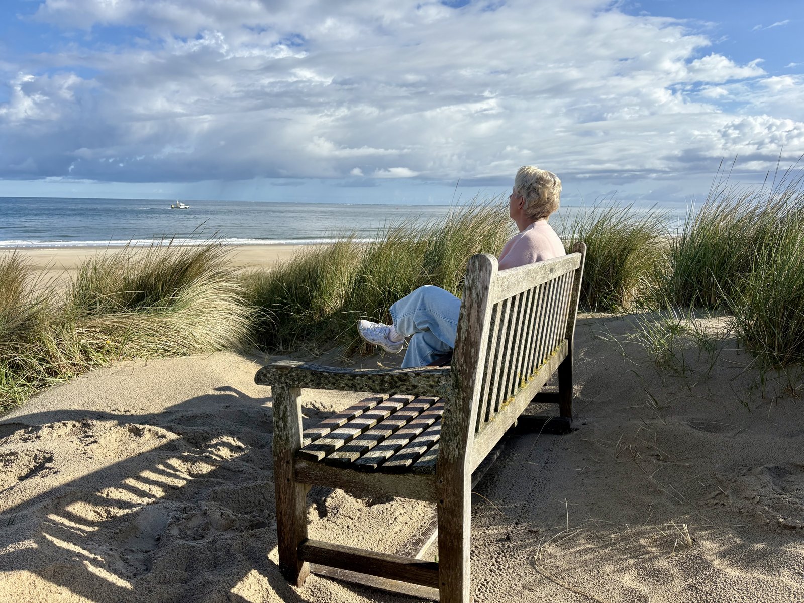 Paulien op een bankje in de duinen, uitkijkend over zee
