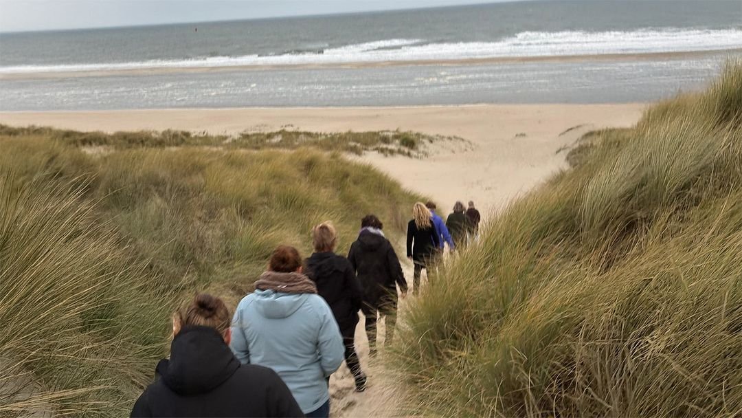 Een retraitegroep loopt door de duinen naar het strand van Vlieland